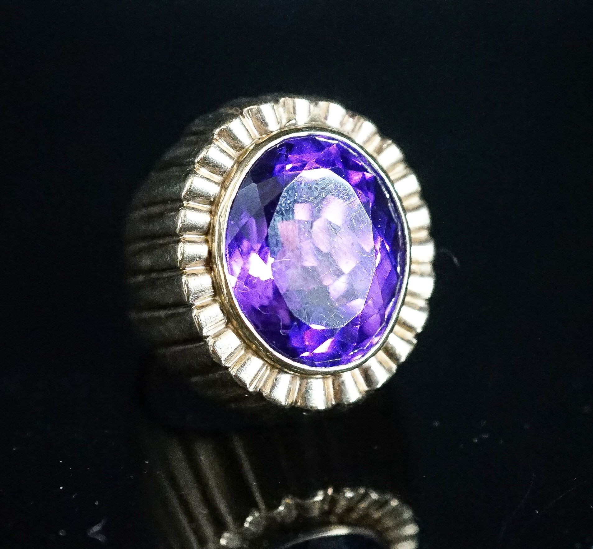 A yellow metal and oval cut amethyst set dress ring, with fluted setting, size Q/R, gross 17 grams.
